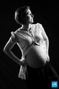 Portrait noir et blanc d'un femme enceinte sur fond noir