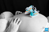 Shooting photo de grossesse, les petites chaussures de bébé sur le ventre